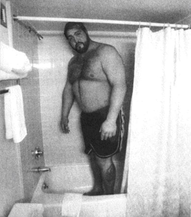 Big Show in a shower on the road having to bend his head which touches the ceiling
