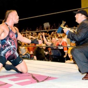 RVD drops to his knees in celebration in the ring as Paul Heyman hands him the WWE Championship after beating John Cena at ECW One Night Stand in 2006.
