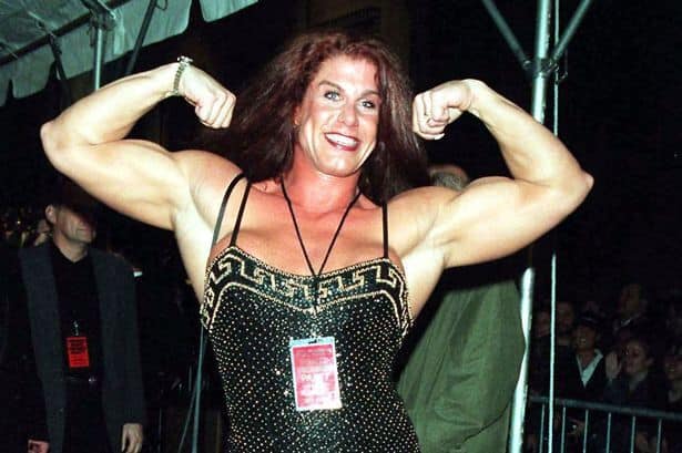 Nicole Bass in a black and gold sequined spaghetti strap dress showing off her arm muscles