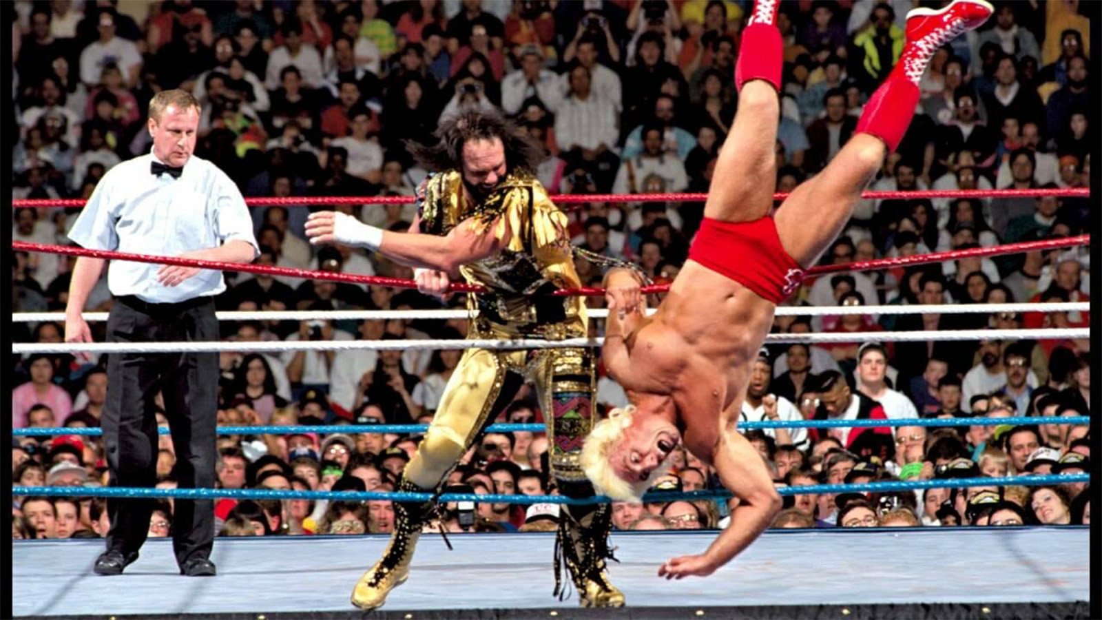 Ric Flair is sent crashing out of the ring by Randy Savage, a perfect example of the high-impact visual drama that defined his classic battles. 