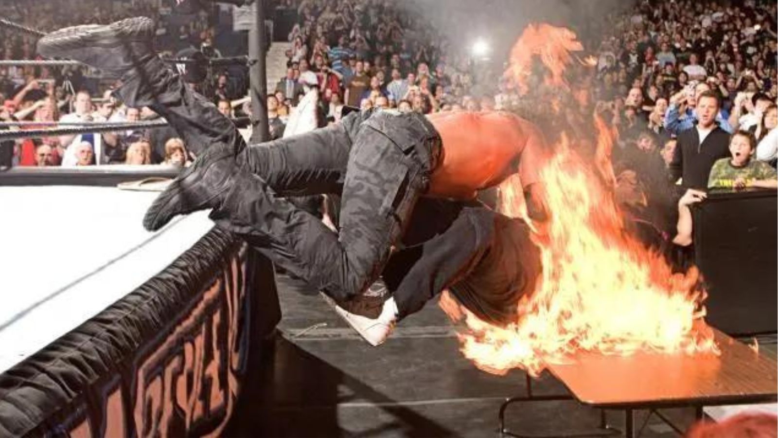 WrestleMania 22 (2006): Edge soars with a Spear, driving Mick Foley off the apron and through a flaming table below. The burn injuries Foley suffered made this one of WWE’s most infamous table spots. 