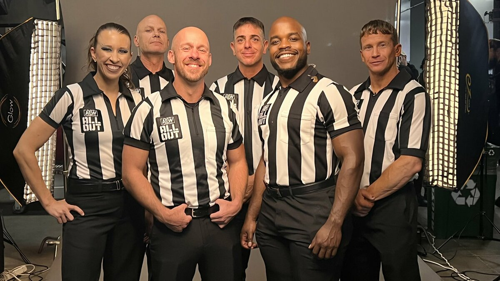 Behind the scenes at AEW All Out in 2021, the AEW referee roster (Aubrey Edwards, Rick Knox, Bryce Remsburg, Paul Turner, Stephon Smith, and Mike Posey) gathers before the opening bout. Their role is to keep matches safe and seamless as they travel the globe together, sharing tips and covering each other’s shows to prevent burnout in an industry where officials often work multiple matches per night. 