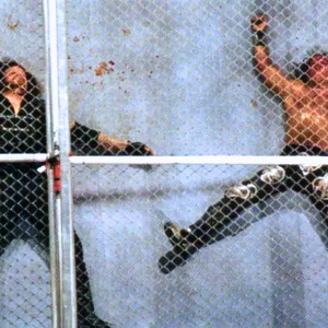 Shawn Michaels and The Undertaker lie battered and bloodied inside the ring following the first-ever Hell in a Cell match at Badd Blood: In Your House on October 5, 1997, in St. Louis, Missouri. Captured from high above the steel structure that changed WWE forever, this iconic shot embodies what Hell in a Cell came to represent – pain, sacrifice, and legacy.