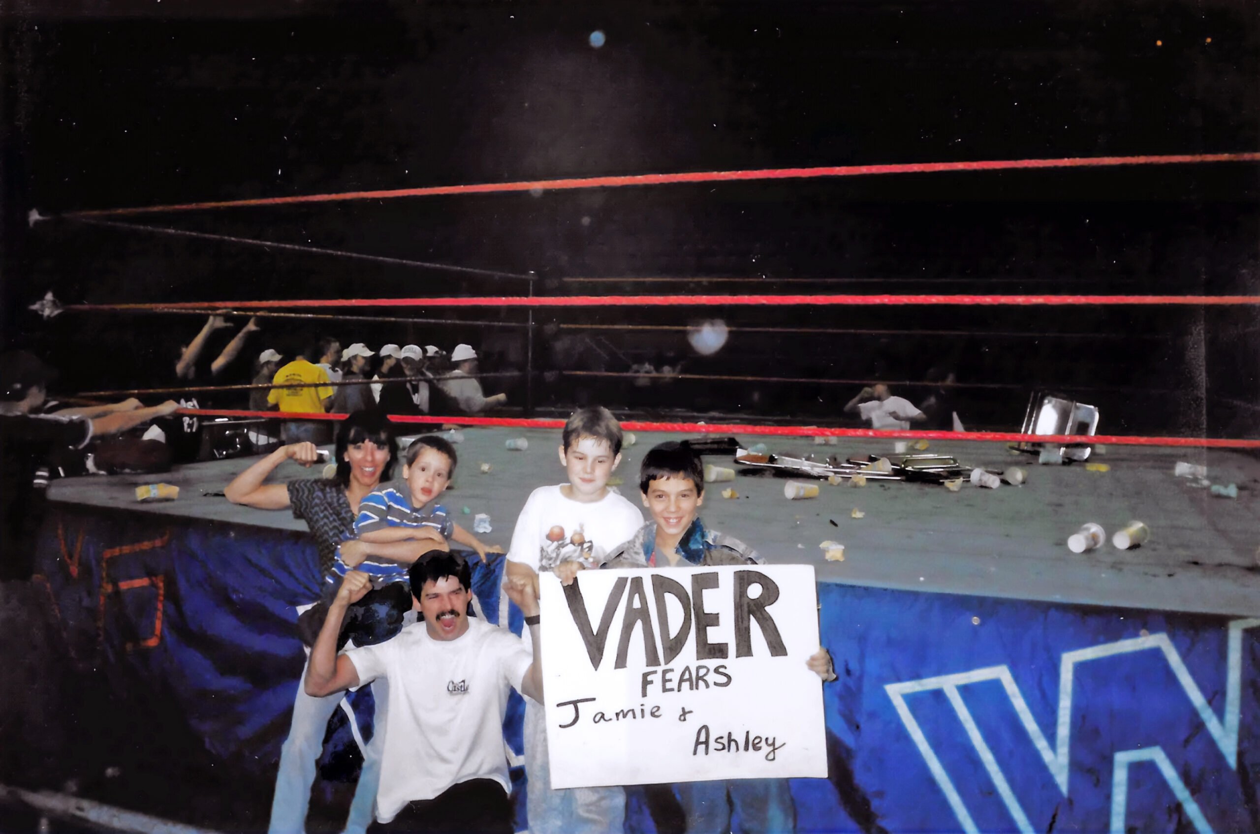 Ryan Henslee poses ringside after 1997 WWE Little Rock riot at Barton Coliseum holding Vader fears Jamie and Ashley sign