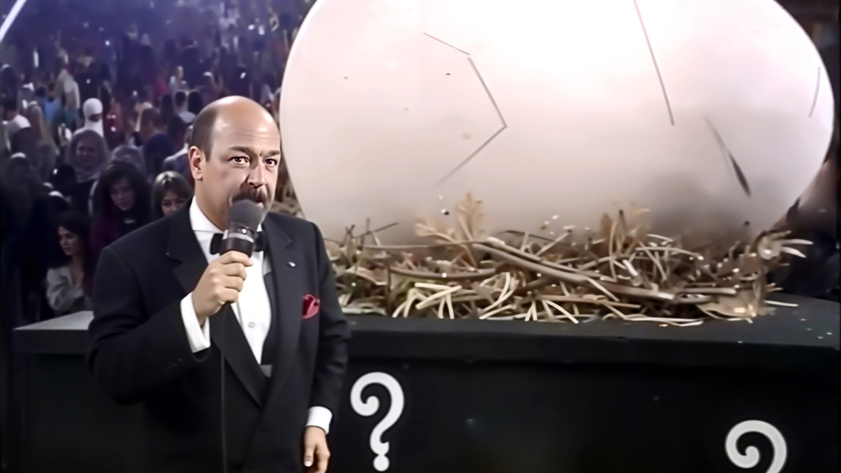Mean Gene Okerlund stands beside the mysterious giant egg at Survivor Series 1990 as the Hartford Civic Center as the crowd buzzes over WWE’s bold Thanksgiving gamble that would hatch the Gobbledy Gooker.