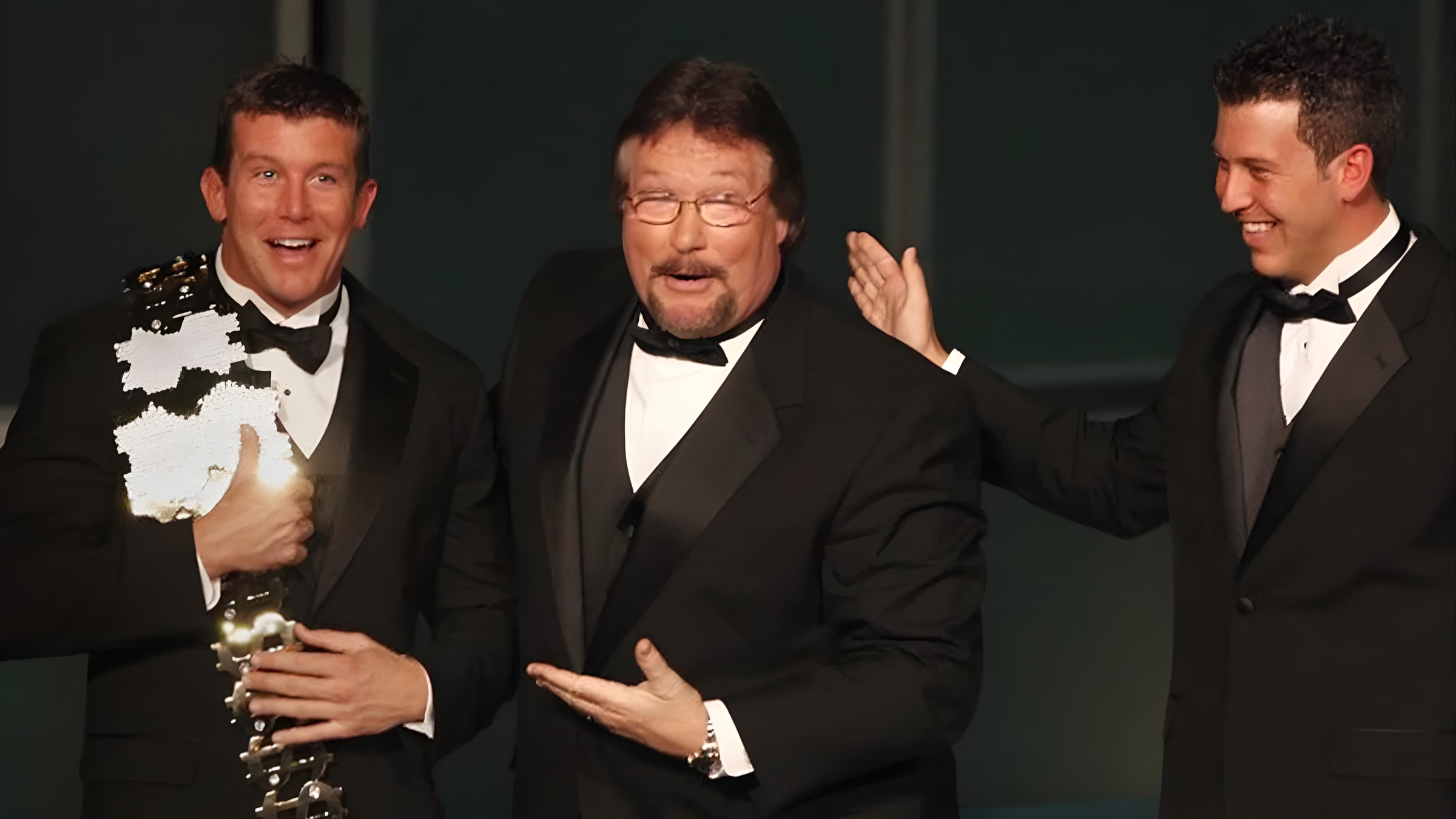 Ted DiBiase Sr. (center), Ted DiBiase Jr. (left), and Brett DiBiase (right) at the 2010 WWE Hall of Fame induction ceremony. Ted Jr. holds his father's iconic Million Dollar Championship belt—a moment capturing the family's wrestling prominence, years before the Mississippi welfare scandal allegations emerged.