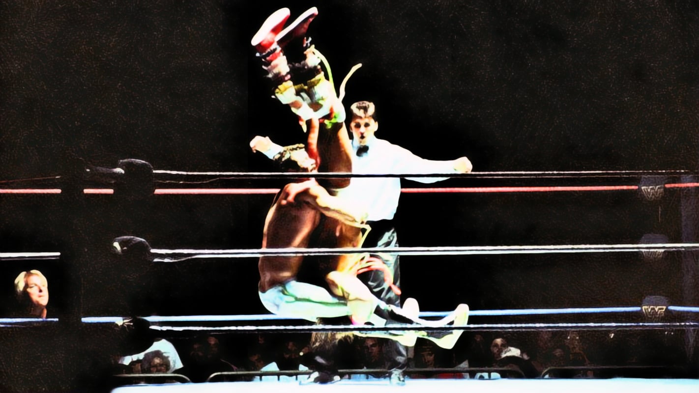 Rick Rude delivers a piledriver to Ultimate Warrior at a WWF house show, with a young Shane McMahon serving as referee and Bobby Heenan watching from ringside. Referee Earl Hebner would later recall that the real-life confrontations between Rude and Warrior extended well beyond moments like this one, including a night in Savannah, Georgia, where the trouble followed Warrior all the way to the parking lot. 