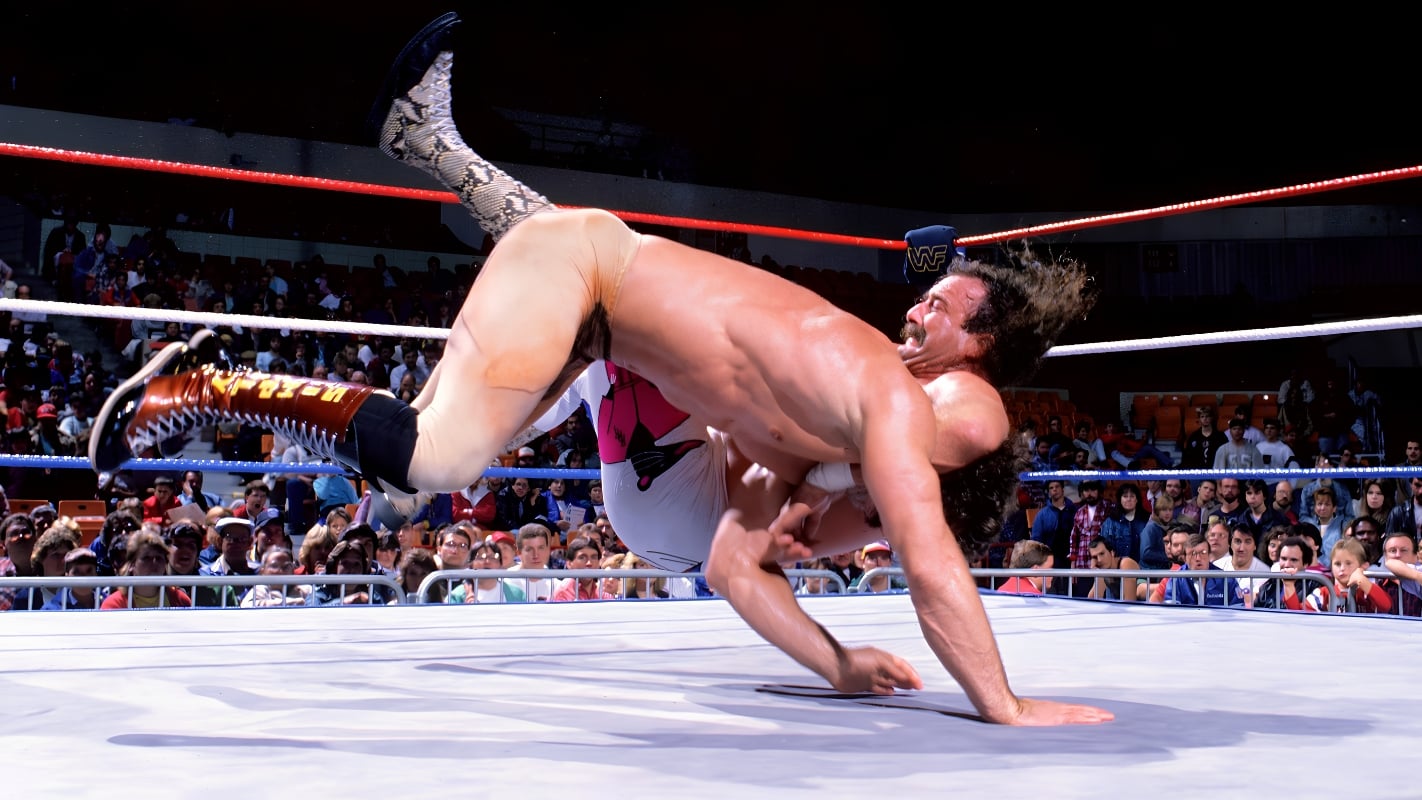 Jake Roberts delivers the DDT to Rick Rude during a 1980s WWE match, a move that once ended bouts instantly and is considered one of the most protected finishers in wrestling history.