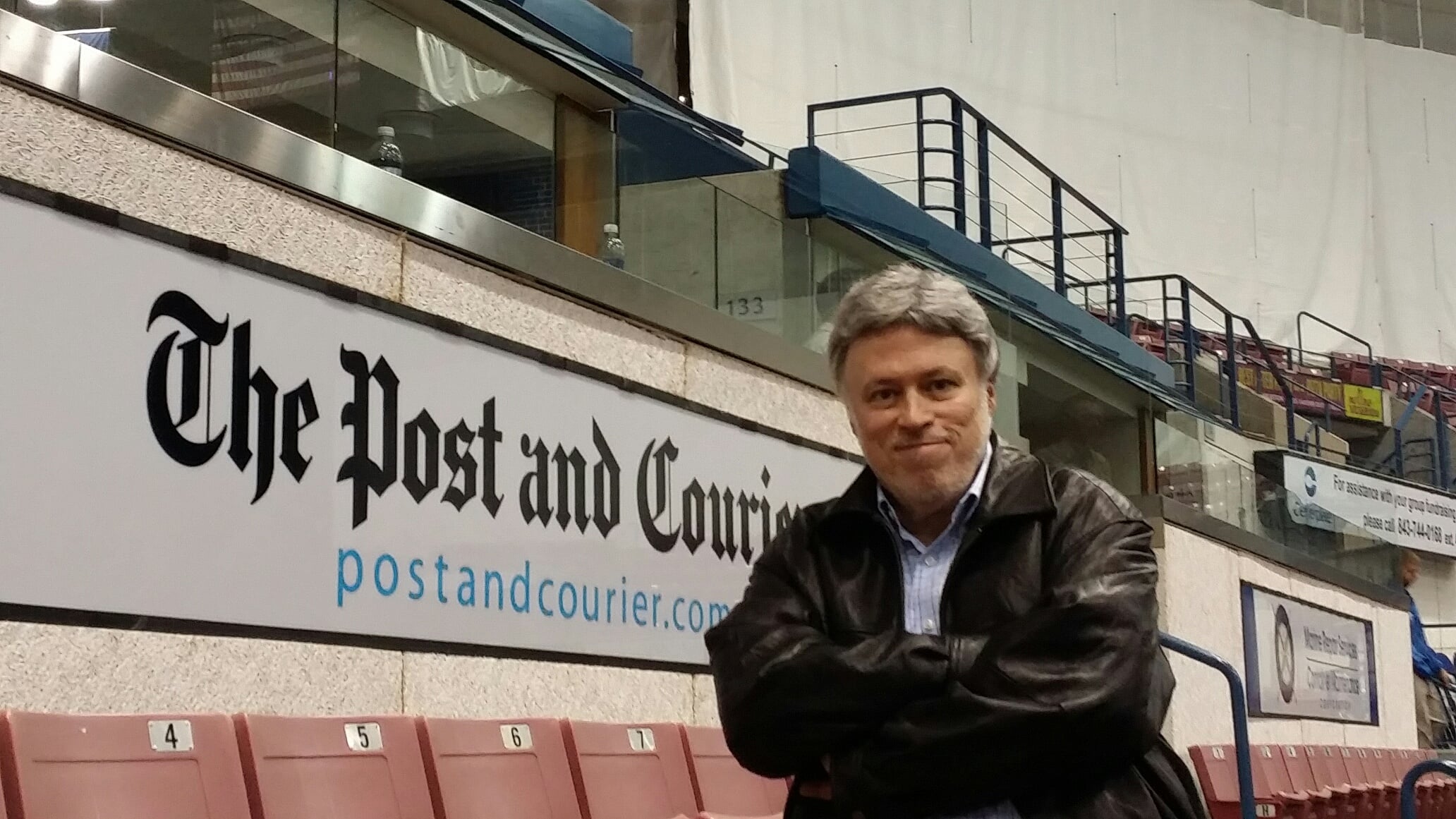 Mike Mooneyham stands beside a Post and Courier newspaper banner in Charleston, South Carolina, home to his decades-long professional wrestling column.